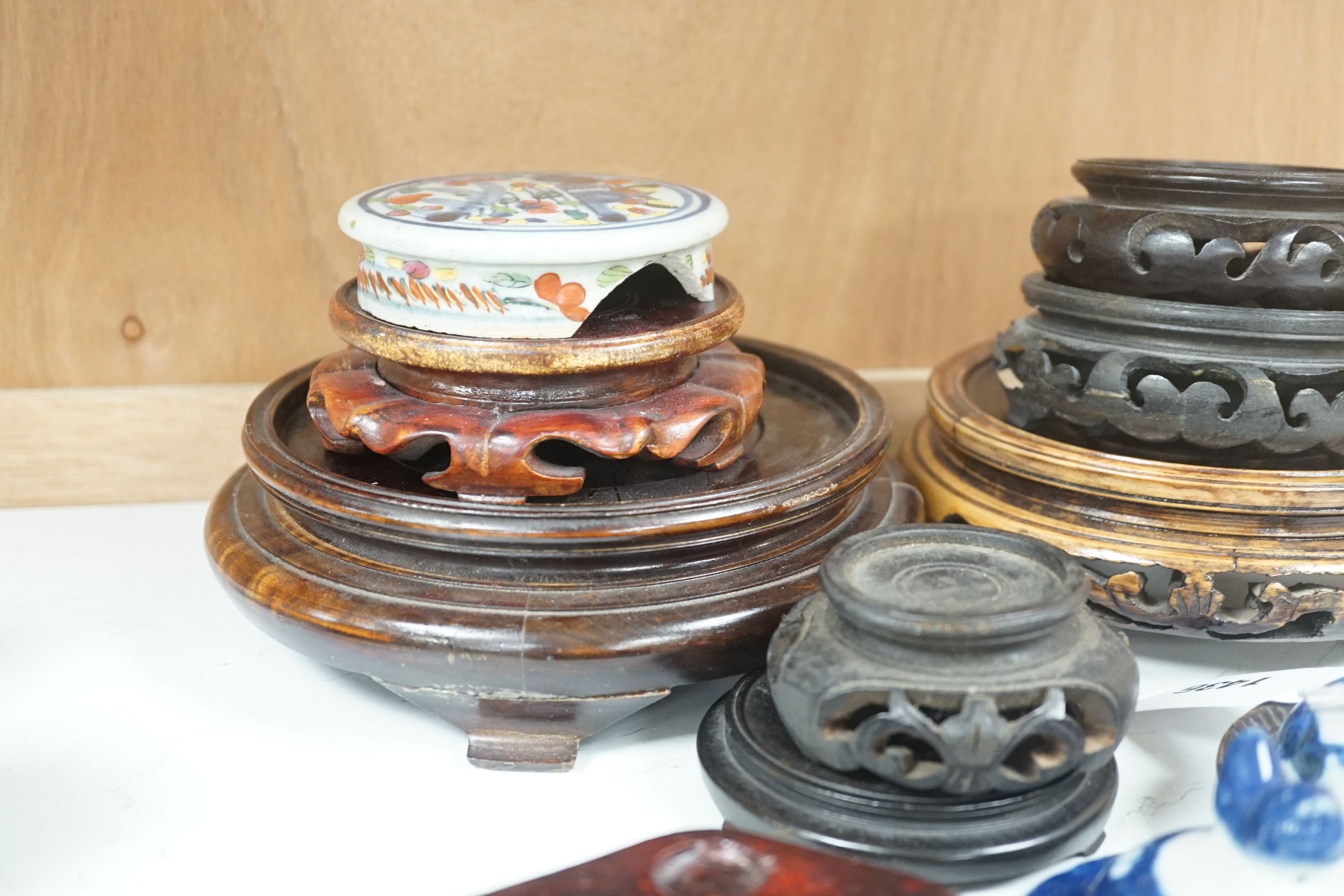 A group of Chinese wooden stands and three ceramics covers.